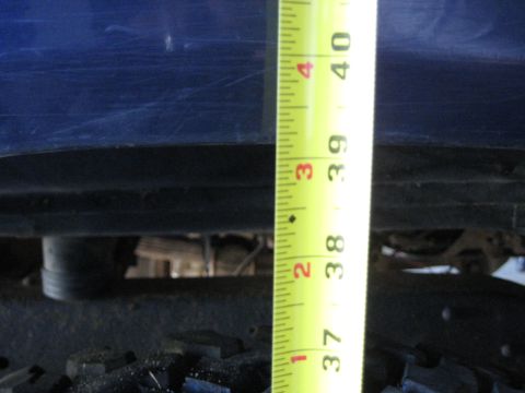 1978 Ford Bronco - A measuring tape is used to show the height of a blue vehicle's body above its suspension and tires.