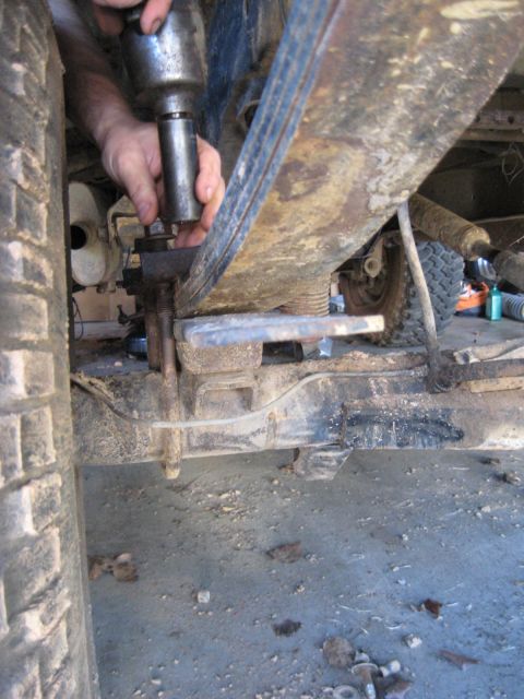 1978 Ford Bronco - Mechanic uses an impact wrench on the leaf spring suspension of a vehicle, focusing on the mechanical components.