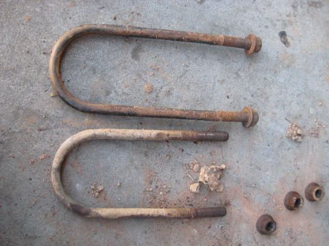 1978 Ford Bronco - Two rusty U-bolts and nuts are shown on a concrete surface.