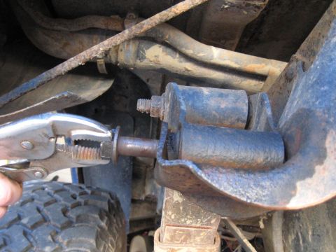 1978 Ford Bronco - Vice grips are used to work on a bolt on the undercarriage of a vehicle.