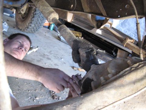 1978 Ford Bronco - A mechanic works on the driveshaft of a vehicle, focusing on the mechanical components beneath.
