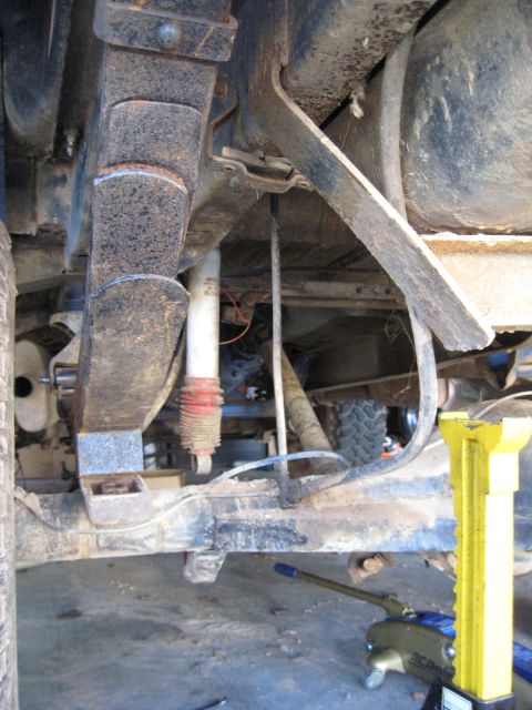 1978 Ford Bronco - The underside of a vehicle is shown with its suspension components and a jack supporting it.