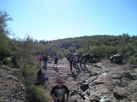 1986 Toyota Hilux - Off-road vehicles parked on a rocky desert trail with people standing around them.