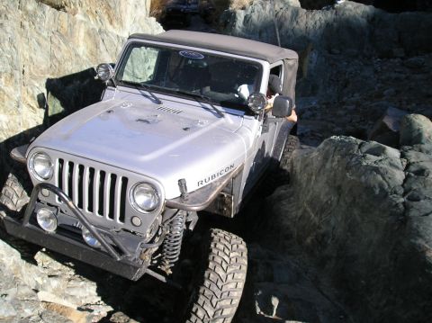 1986 Toyota Hilux - A silver Jeep Wrangler Rubicon navigates a rocky trail, with another vehicle visible in the background.