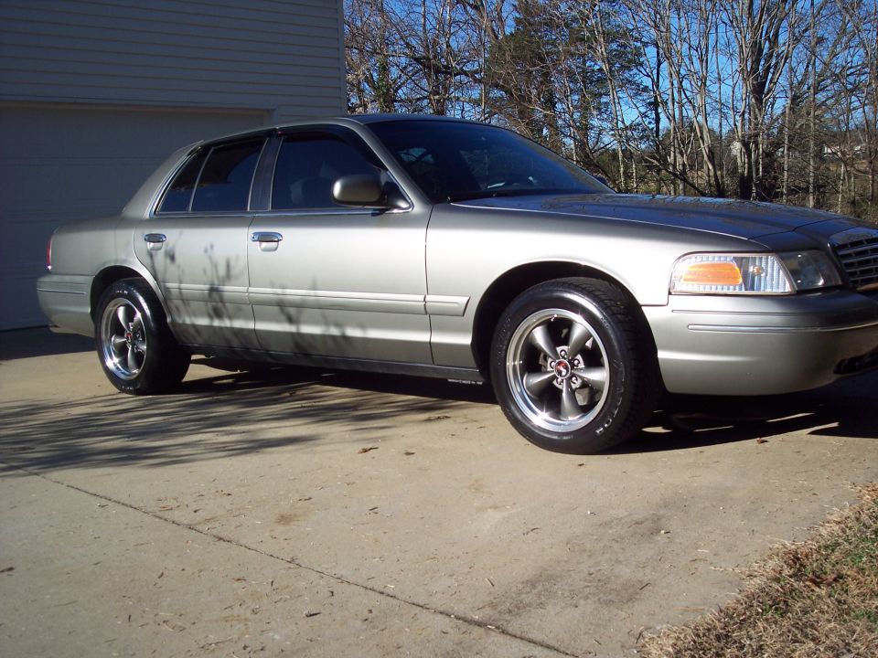 Silver 2000 Ford Crown Victoria with aftermarket wheels parked on a concrete driveway