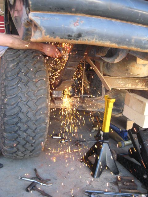 1978 Ford Bronco - Mechanic cuts a leaf spring on a lifted vehicle, creating a shower of sparks.
