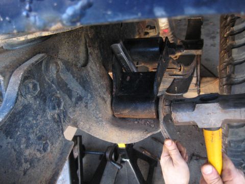 1978 Ford Bronco - Mechanic works on a vehicle's suspension system, focusing on a specific part.