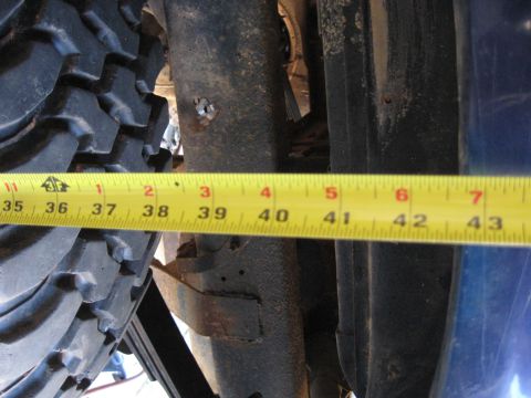 1978 Ford Bronco - A tape measure is used to measure the clearance of a vehicle's frame near the tire.