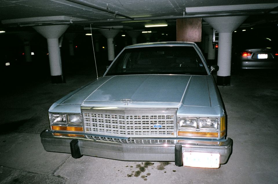Front of a light blue Ford LTD sedan with grille in a parking garage