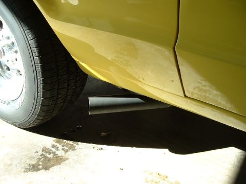 1978 Ford Ranchero - A close-up view of a yellow vehicle's side, showing the exhaust pipe and a portion of the wheel.