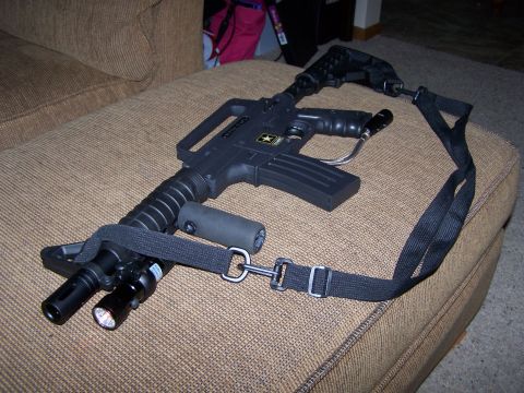 1986 Ford Bronco - A paintball gun with tactical accessories is displayed on a textured couch surface.