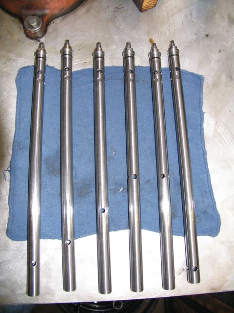 1984 Ford Bronco - Seven valve lifters are arranged on a blue cloth on a metal surface, likely in a workshop.