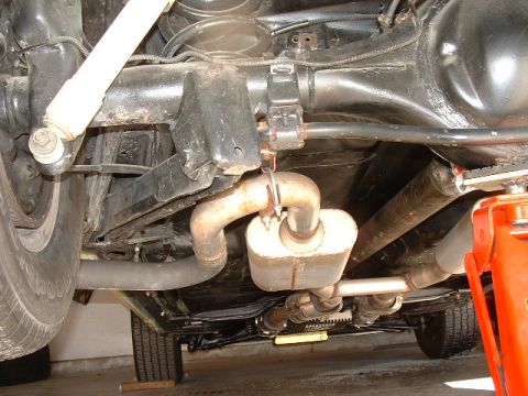 1978 Ford Ranchero - A view from underneath a vehicle shows the exhaust system, rear axle, and suspension components, with a jack supporting the frame.