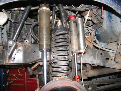 1984 Ford Bronco - Close-up view of modified front suspension components, including shocks and coil springs, on a vehicle.