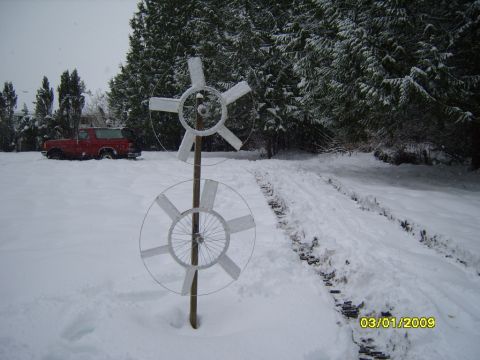 1989 Ford Bronco - A red SUV sits in a snow-covered yard next to a homemade wind turbine on a cloudy day.