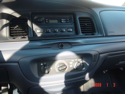 2000 Ford Crown Victoria - The dashboard features an AM/FM radio, climate controls, and an airbag indicator.