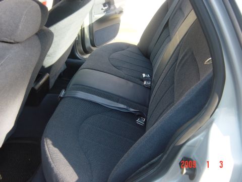 2000 Ford Crown Victoria - Interior view of the rear seats and seatbelts in a 2000 Ford Crown Victoria, showing the fabric upholstery and door panel.
