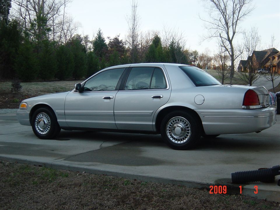 Silver 2000 Ford Crown Victoria parked on driveway. Side view shows the car's profile