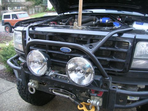 1996 Ford Bronco - Front view of a black Ford Bronco with an aftermarket bumper and lights, with another Bronco in the background.