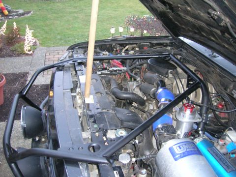 1996 Ford Bronco - Engine bay of a 1996 Ford Bronco with a custom roll cage and aftermarket components visible.