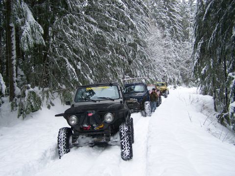 1988 Suzuki Samurai - Off-road vehicles navigate a snow-covered forest path.
