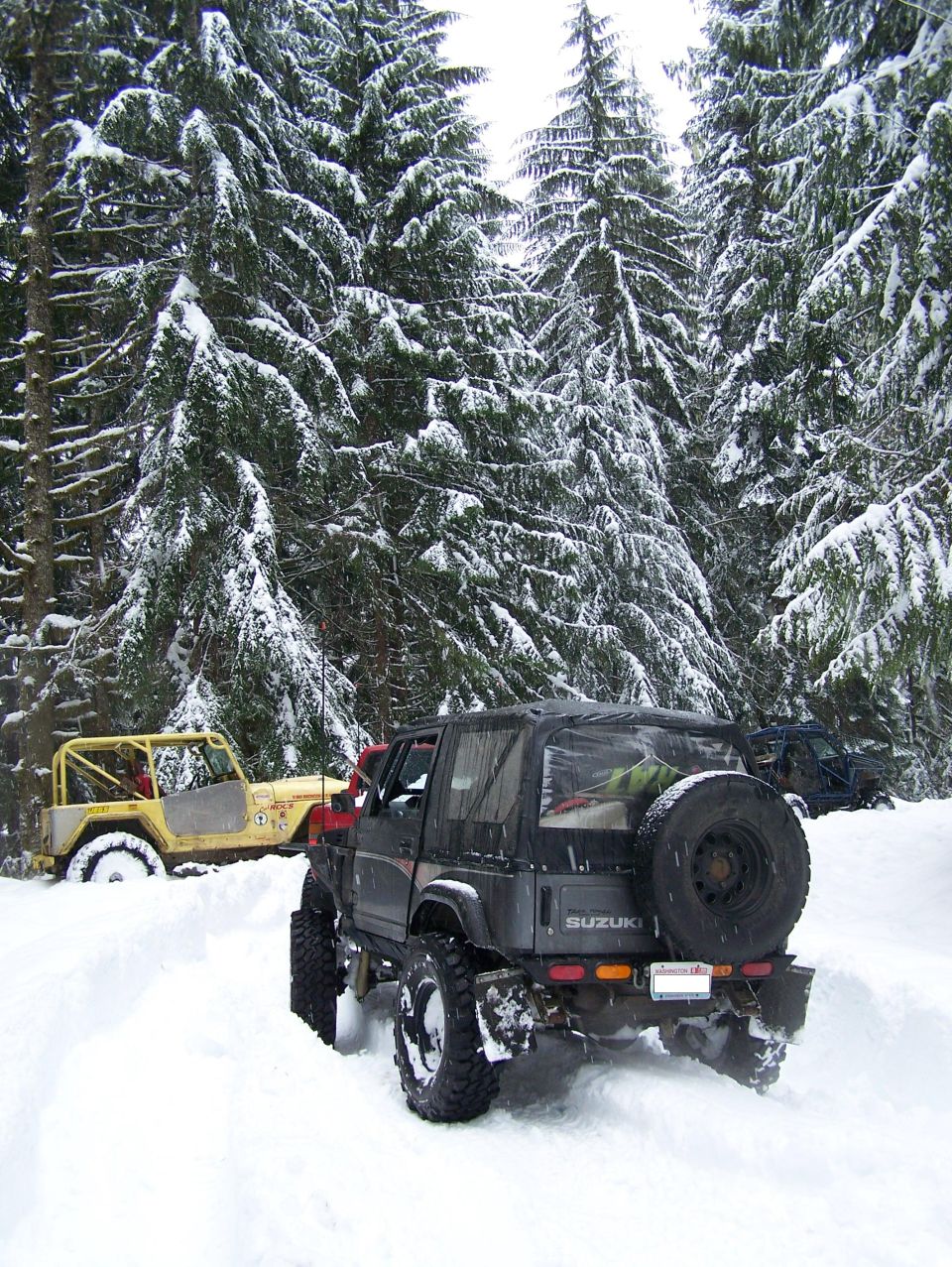Black 1988 Suzuki Samurai with spare tire on rear in snow