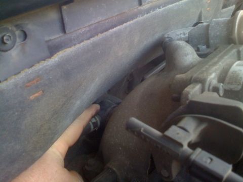 2007 Ford Mustang - A finger points to a hose clamp in the engine bay of a vehicle.