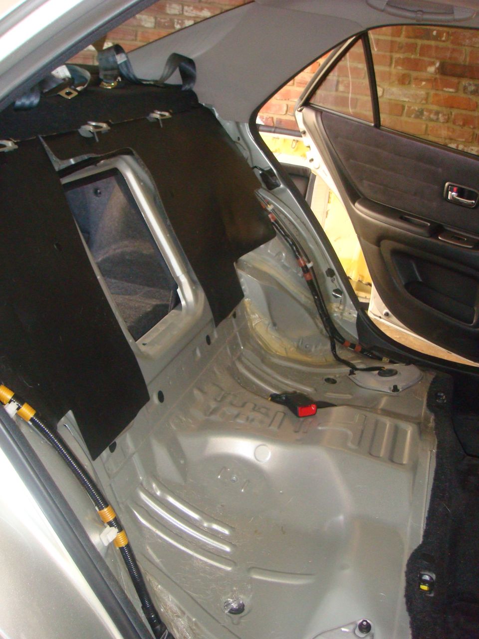 Stripped rear interior of a silver sedan showing bare floor pan and wiring