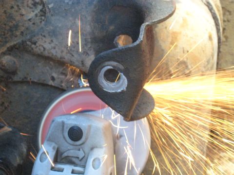 1978 Ford Bronco - Grinding a metal bracket with an angle grinder, sparks flying.