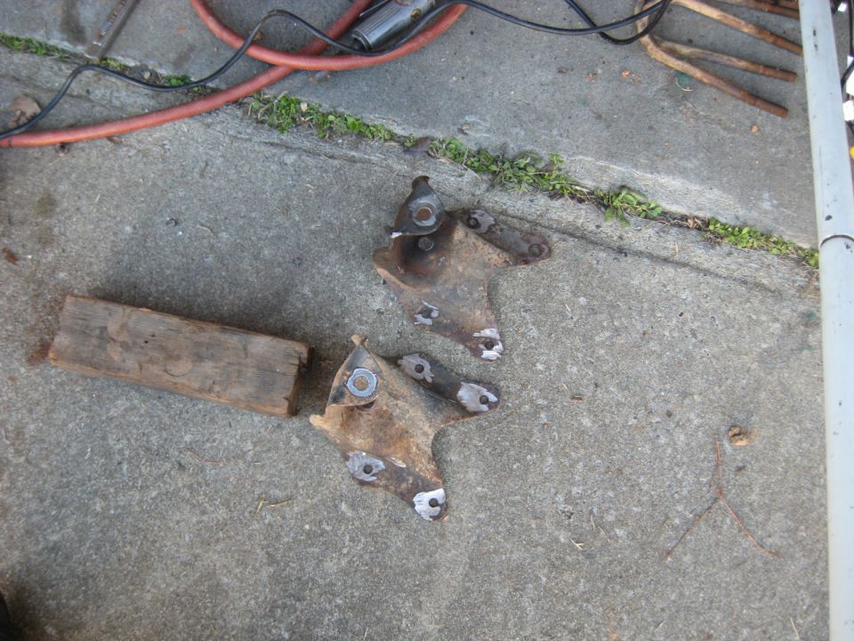 Rusty metal vehicle suspension components on concrete with a wooden block