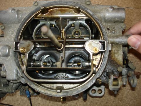 1987 Ford Crown Victoria LTD - A hand is shown adjusting a linkage on a carburetor, likely during a rebuild or tune-up.