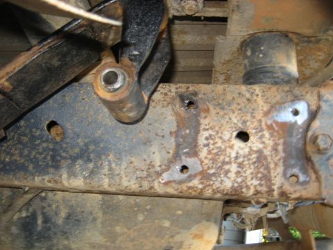 1978 Ford Bronco - Detail of a corroded vehicle frame showing suspension attachment points and signs of repair.