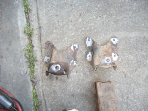 1978 Ford Bronco - Two metal brackets sit on a concrete surface next to a piece of wood.