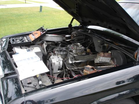 1987 Ford Crown Victoria LTD - Working on the engine of a 1987 Ford Crown Victoria LTD, with tools and manuals laid out.