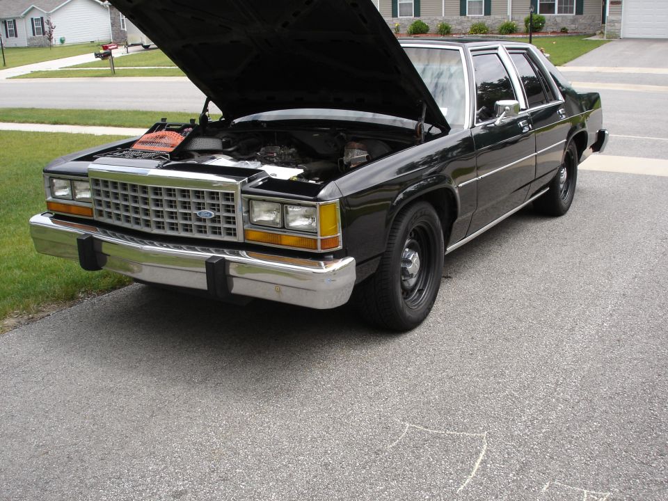 Black Ford LTD Crown Victoria sedan with hood open in a driveway