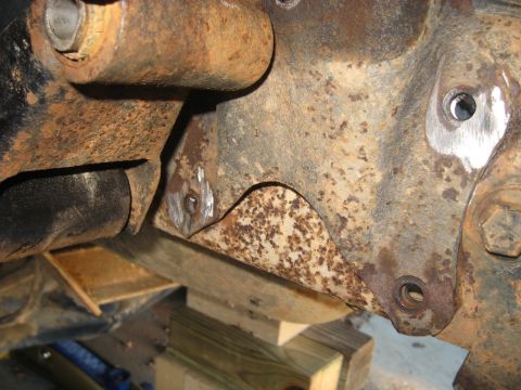 1978 Ford Bronco - The heavily rusted frame components of a vehicle are visible, supported by wooden blocks for maintenance.