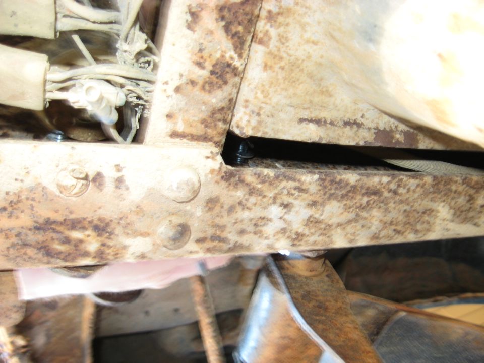 Close-up of rusted metal frame with wires and a strap visible
