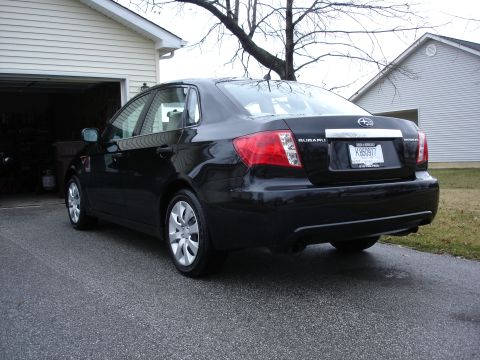 2008 Subaru Impreza - A black 2008 Subaru Impreza sedan is parked in front of a garage.