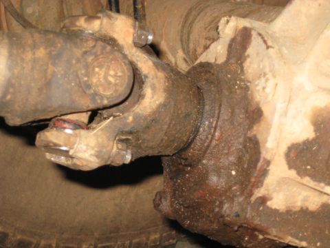 1978 Ford Bronco - Underbody photograph of a rusty driveshaft U-joint and differential, not a technical document.