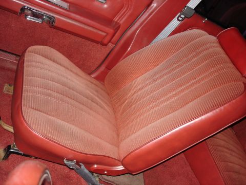 1987 Ford LTD Crown Victoria - Overhead interior shot of a red ribbed-velour and vinyl bench seat with matching red door panel, armrest and chrome door handle at upper le…