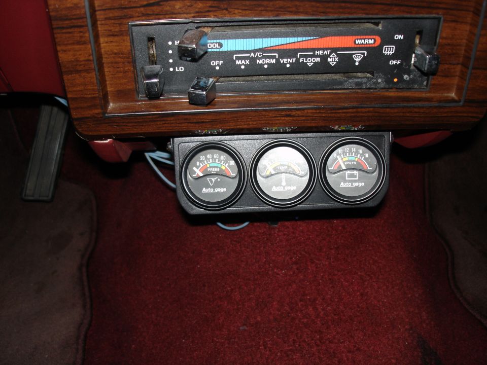 Under-dash Autogage triple gauge pod with oil pressure, temp and volt gauges over red carpet