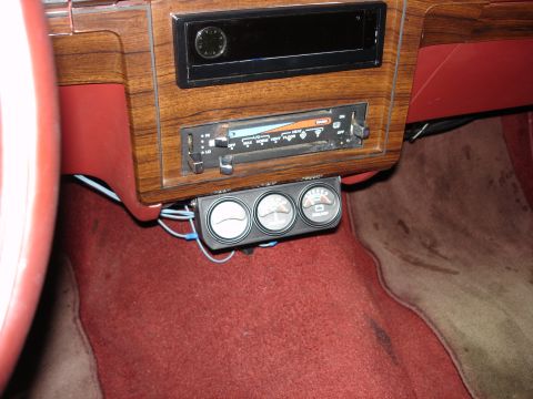 1987 Ford LTD Crown Victoria - Interior shot of a red-trimmed dash with woodgrain center stack, showing an empty radio opening with analog clock above the slide-lever A/C…