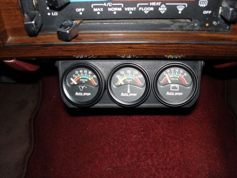 1987 Ford LTD Crown Victoria - Three Auto Gage brand gauges are mounted under the dashboard of a vehicle. The gauges measure oil pressure, engine temperature, and voltage.
