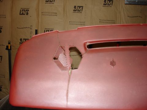 1987 Ford LTD Crown Victoria - A close-up view of a damaged red car dashboard with a large hole and cracks. The background shows insulation material with text.