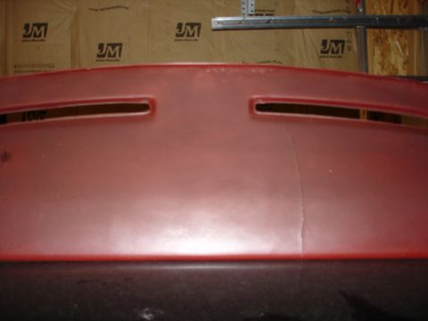 1987 Ford LTD Crown Victoria - A close-up, straight-on view of a red dashboard with two horizontal vents. A vertical crack is visible in the center of the dashboard.