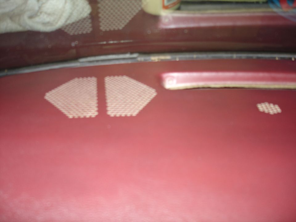 Maroon dashboard with two triangular perforated speaker grilles.