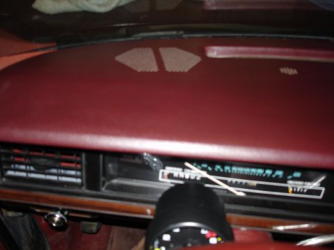 1987 Ford LTD Crown Victoria - Interior view of a car dashboard, focusing on the instrument cluster and air vents. The dashboard is a dark red color, with a wood-grain tr…