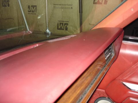 1987 Ford LTD Crown Victoria - Close-up view of the red interior of a car, focusing on the dashboard and a portion of the door panel. The dashboard appears to be made of…