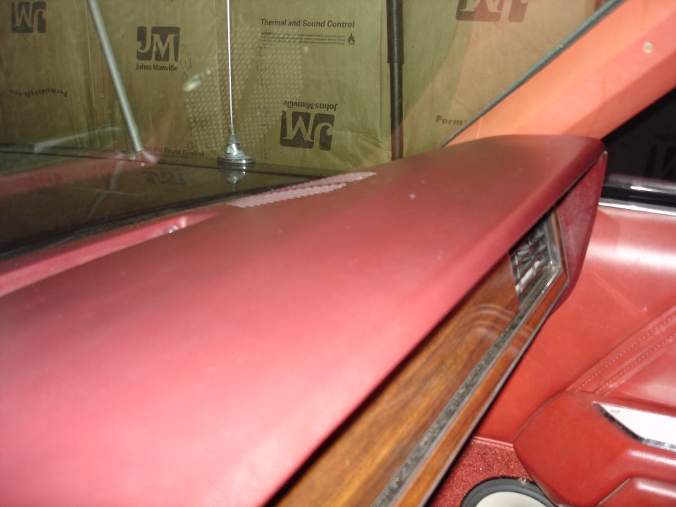 Close-up of a red car interior dashboard with wood grain trim.