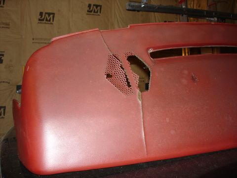 1987 Ford LTD Crown Victoria - A damaged red dashboard panel with a large tear and a perforated section is shown in a close-up view. The background shows a wall with a "J…